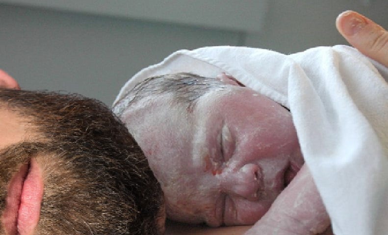 Newborn baby lying on a man’s chest.