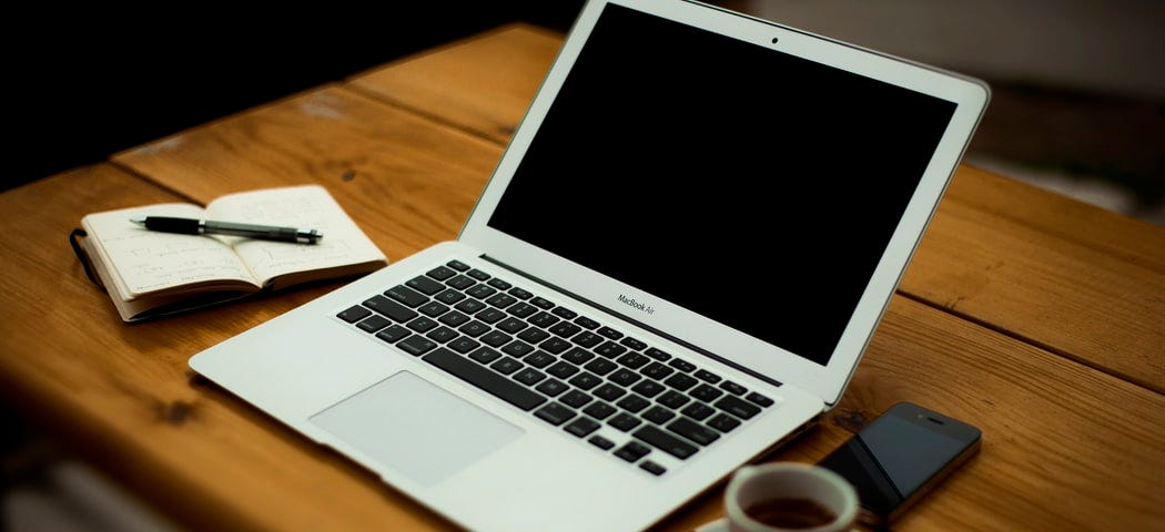 iphone, laptop, and pen on a table