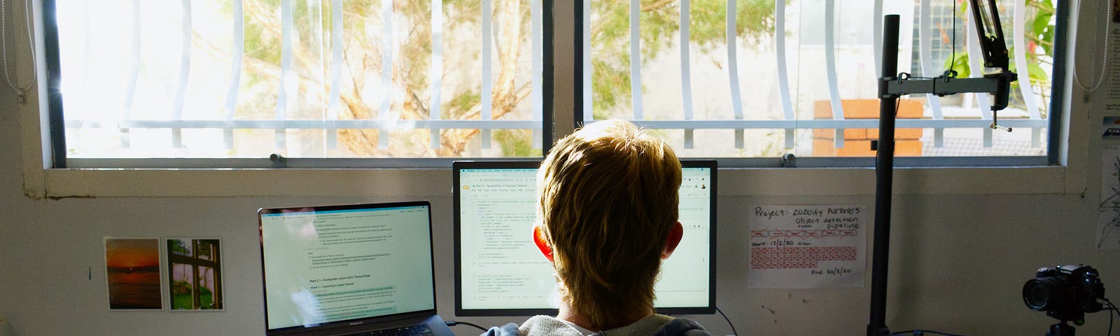 man with a mullet sitting at computer desk with camera on right and microphone over the top