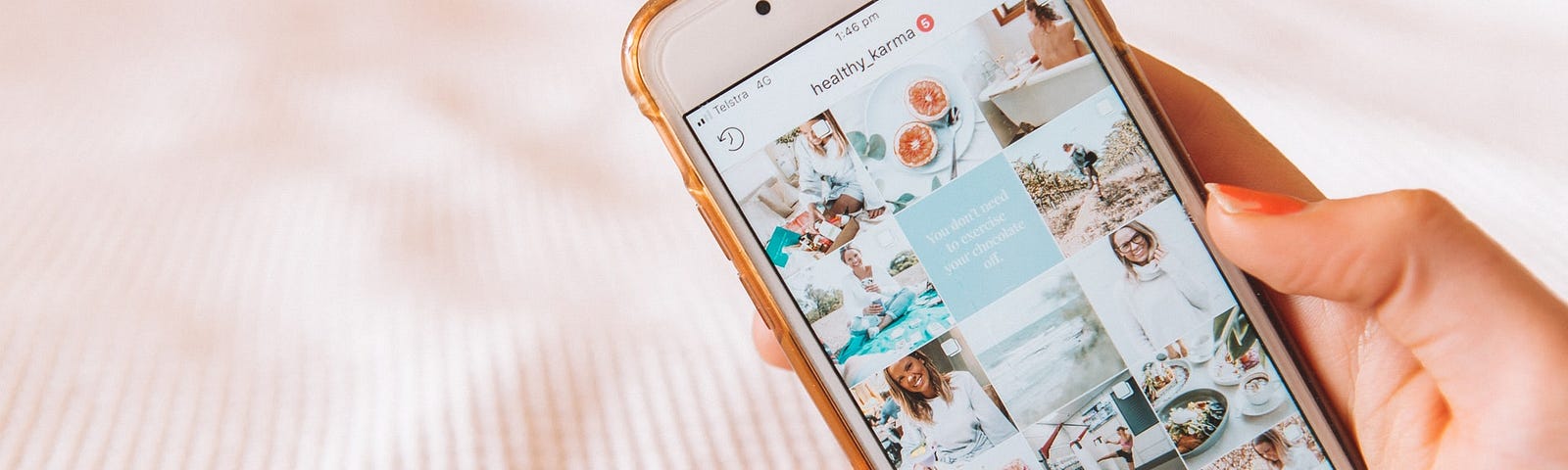 A hand holding a cell phone, can see an Instagram profile of images focused on wellness