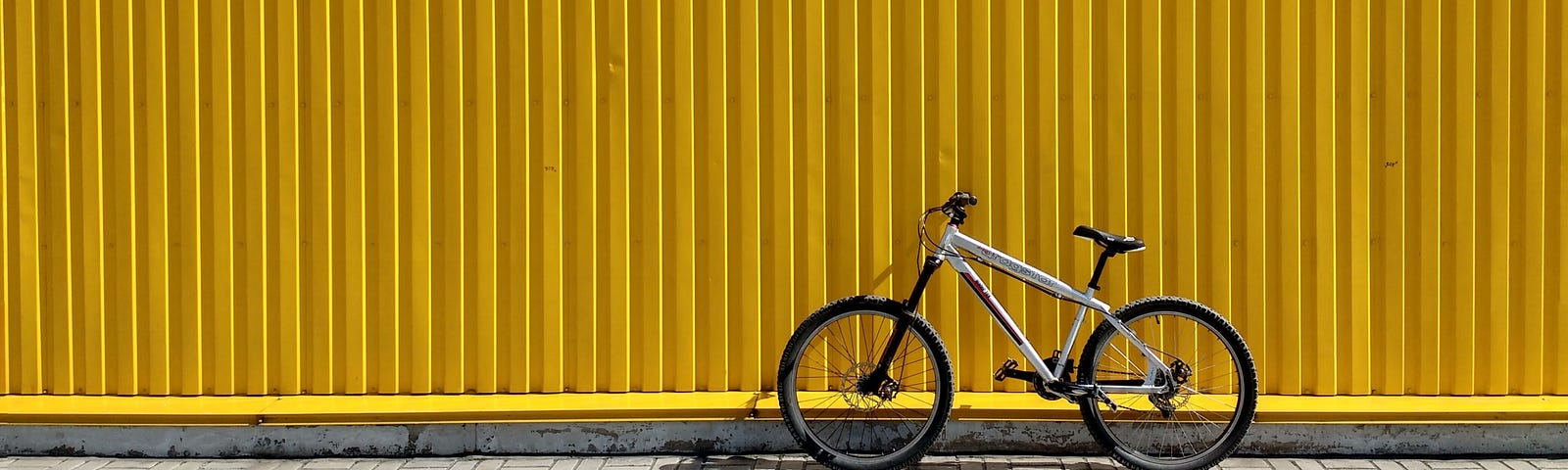 A bike leaning against a yellow wall, decorative image.
