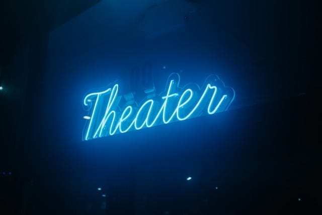 “theatre” in neon blue over black background