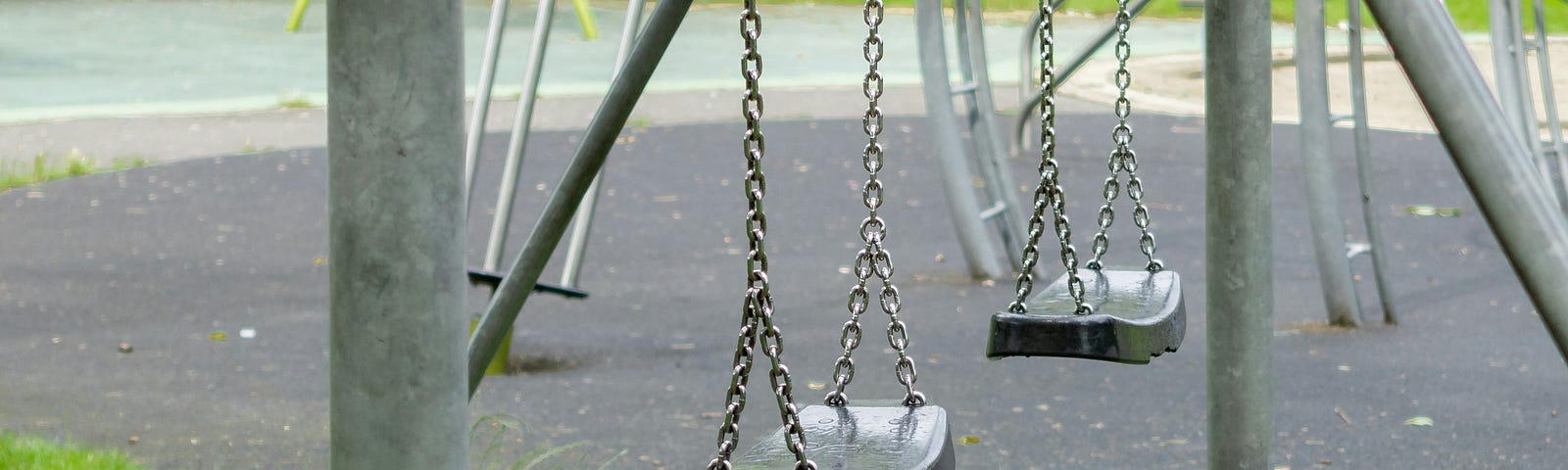 Closeup of a swing set at a playground.