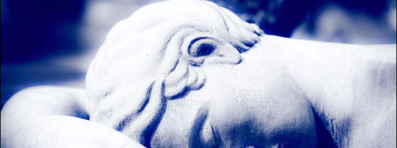 Fotografia em tom azulado de uma escultura de cimento com enquadramento no rosto.