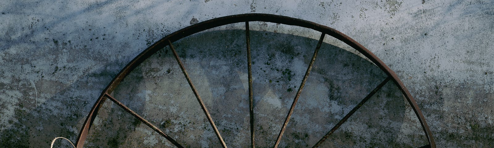 An old, metal wheel leans against a natural gas tank in the yard.