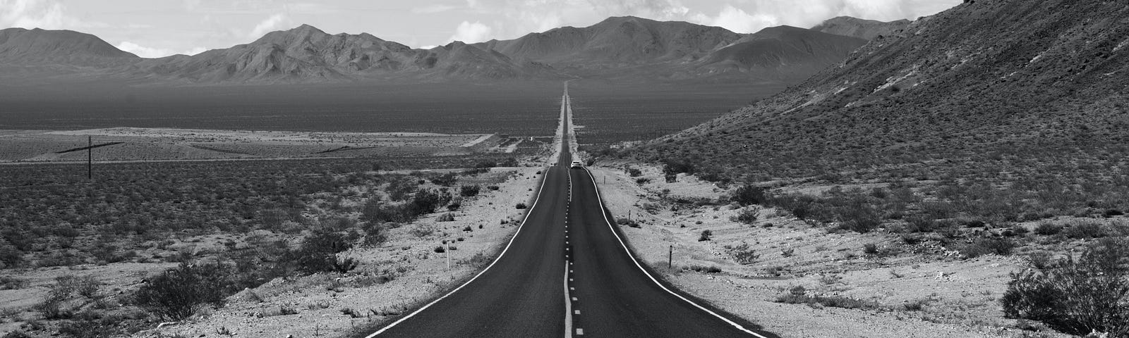 black and white photo of a highway road leading to the horizon
