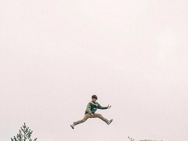 Boy jumping in the air playing an air guitar.