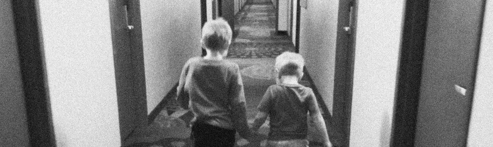 Black and white pic of my two young boys walking hand-in-hand down a hallway. Picture taken from behind them.