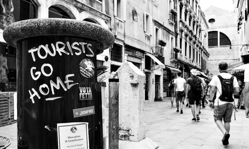 An image of a street scene with the words Tourists Go Home sprayed on a postal box.