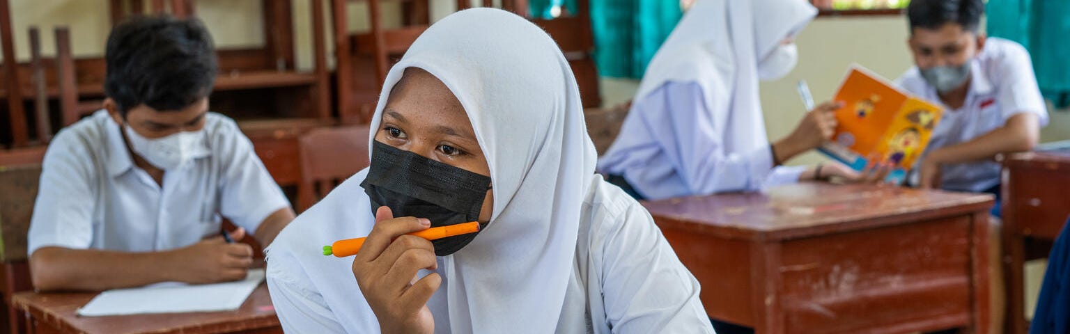 Four students wear masks and work in the notebooks