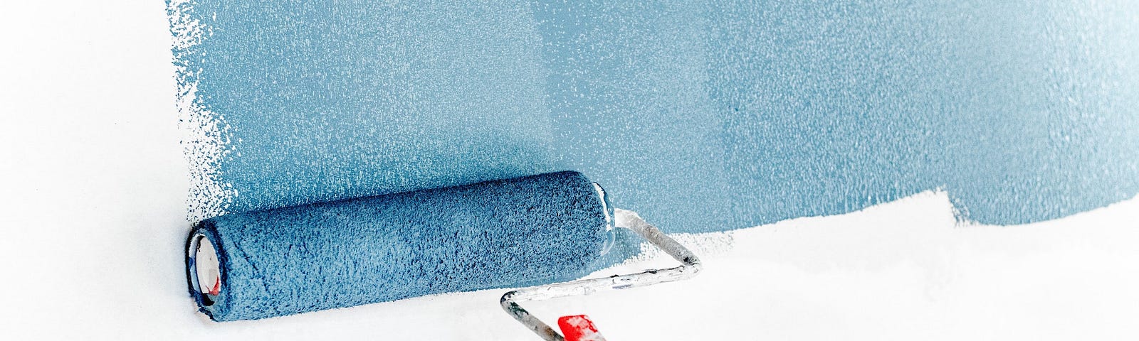 A paint roller applying blue paint to a white wall.