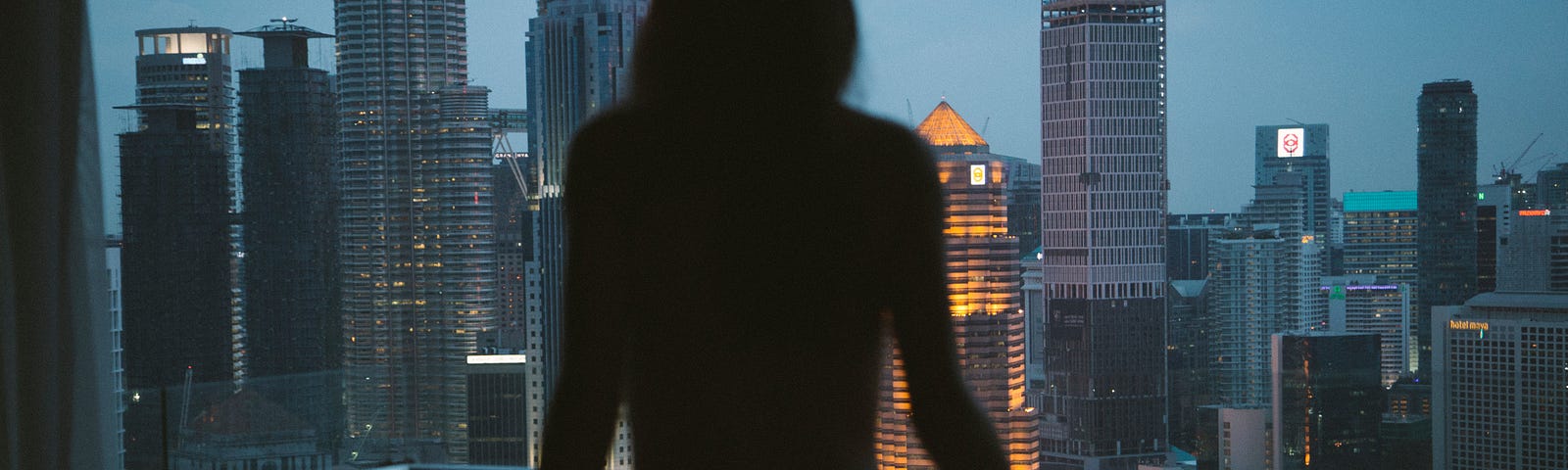 Photo of a female’s back, looking out to the city.