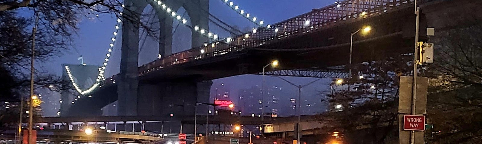 A photo of the Brooklyn Bridge taken from street level on the Manhattan Side of the bridge