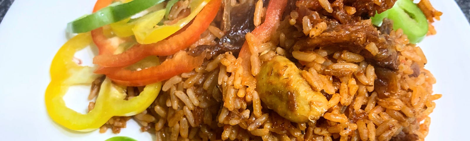 A plate of jolof rice garnished with bell peppers.