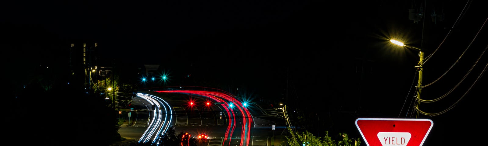 A photo at night of a yield sign near a busy highway.