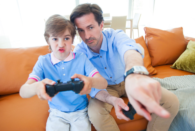 Father and son playing videogame, father instructing son.