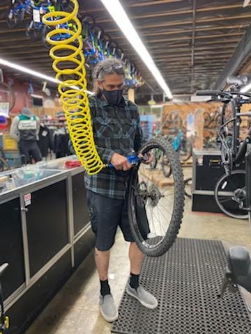 Bike mechanic Gino fills a bike tire with air inside the Sports Basement store.