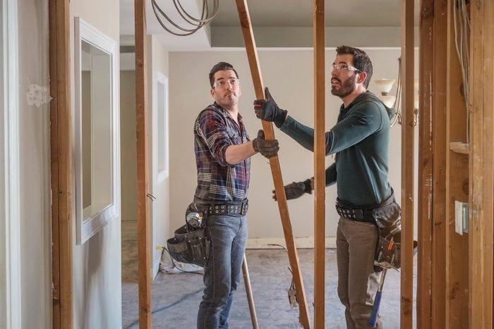 Two men carrying a house pillar