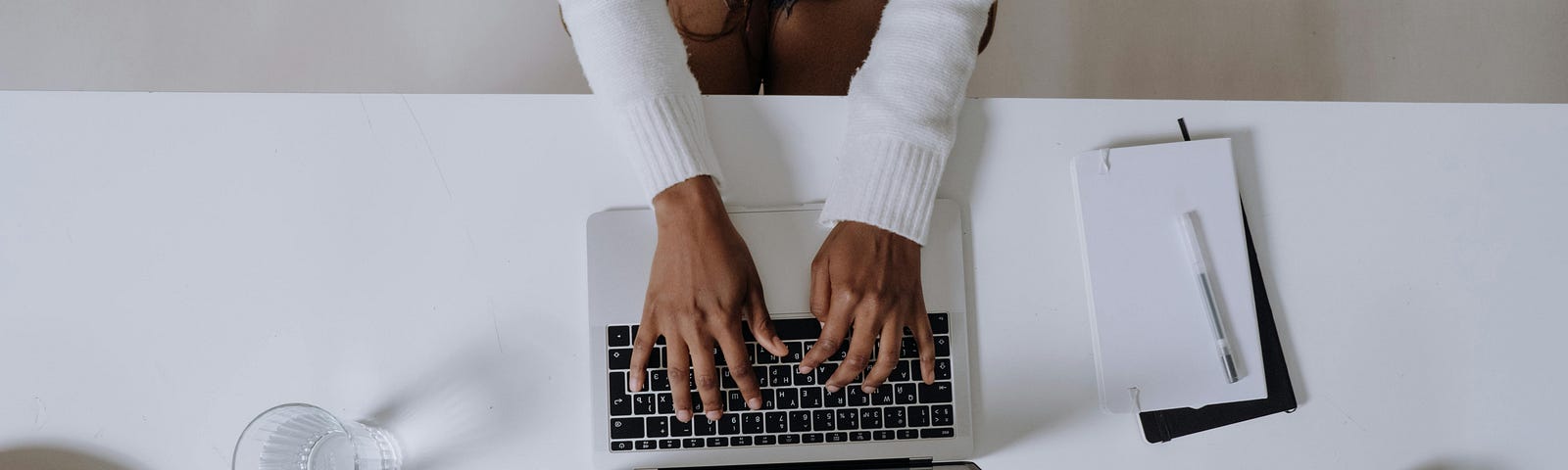 woman in white long sleeve shirt using a Macbook pro on a white desk