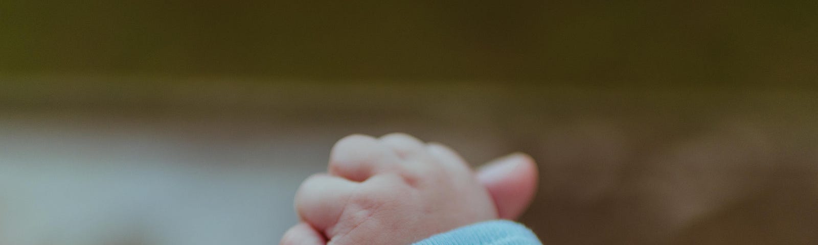 An adult hand holding a newborn’s hand