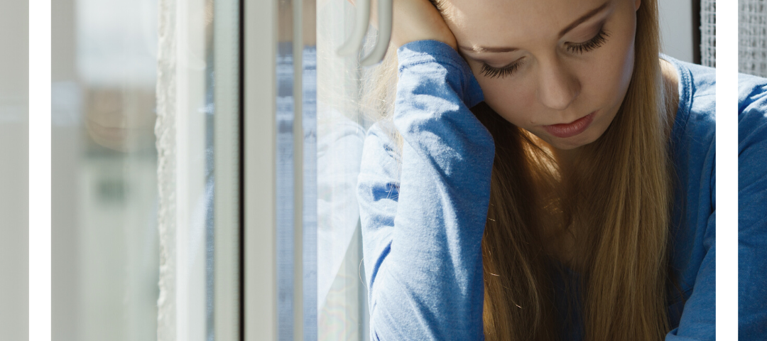 photo of a teenage girl sitting close to a window in deep thought