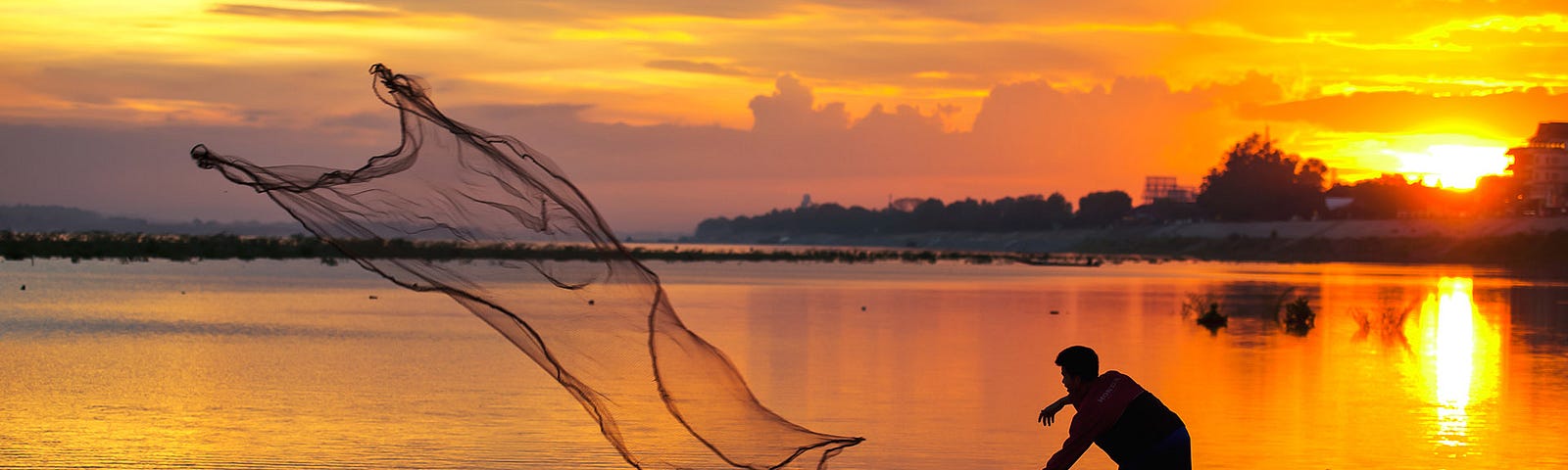 Man throwing his fishing net into the sea.