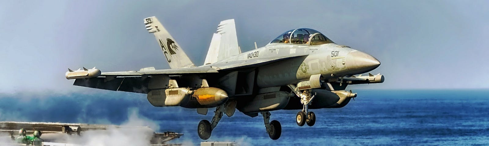 A Navy fighter jet taking off from an aircraft carrier