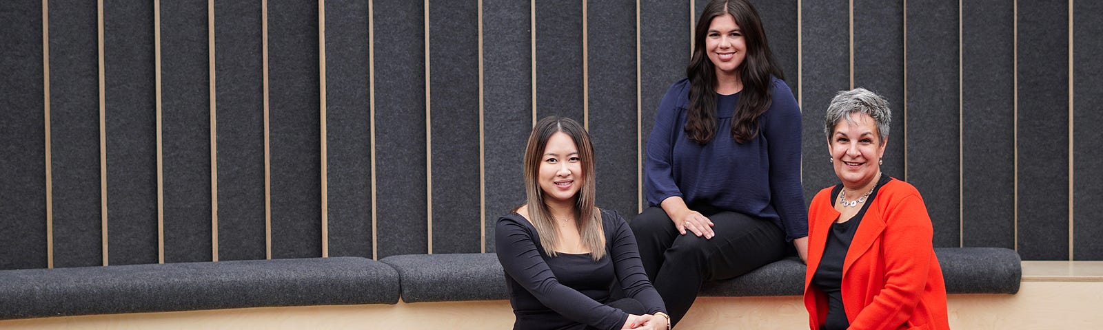 Three women sitting in a small auditorium smiling