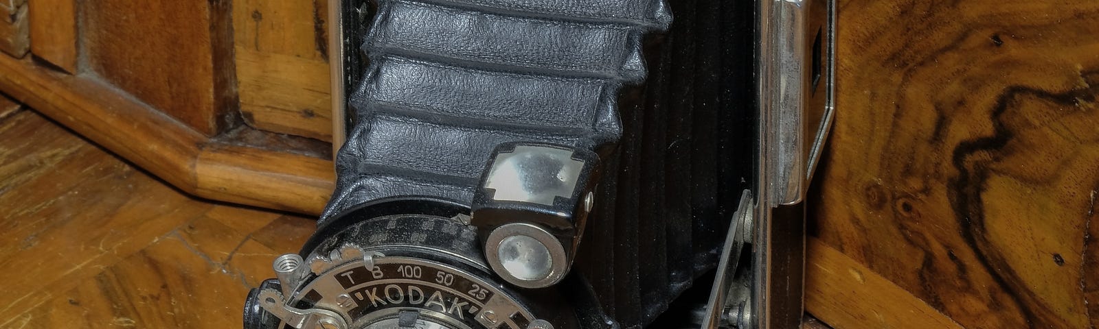 Antique Kodak camera on a table with a pair of pince nez glasses and old pocket watch