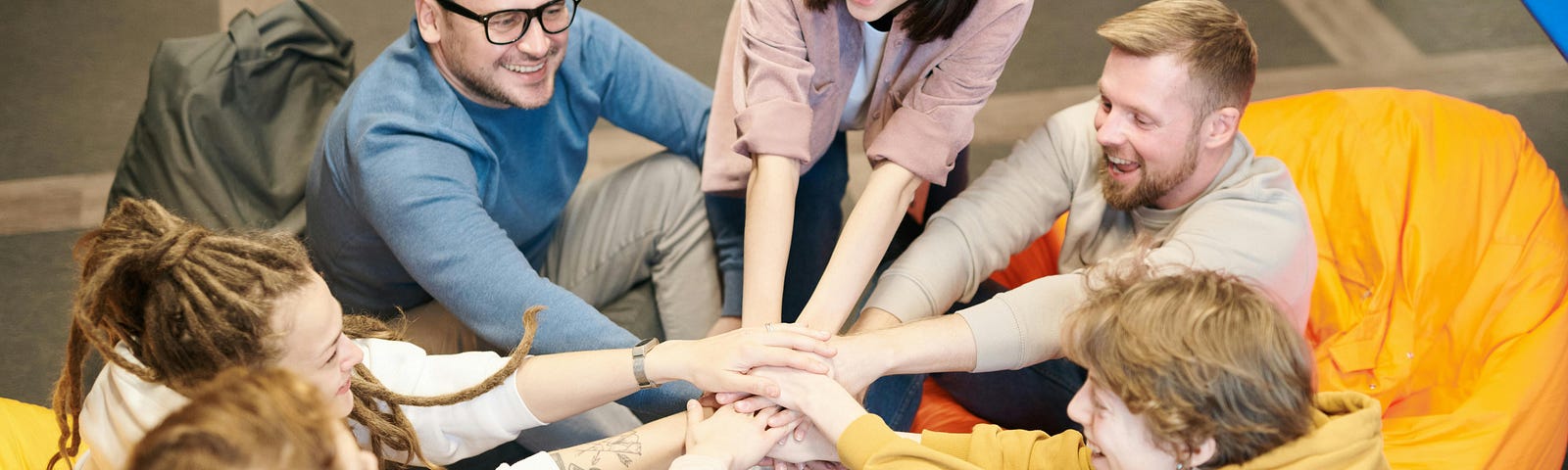 Photo of a team of people joining hands together.