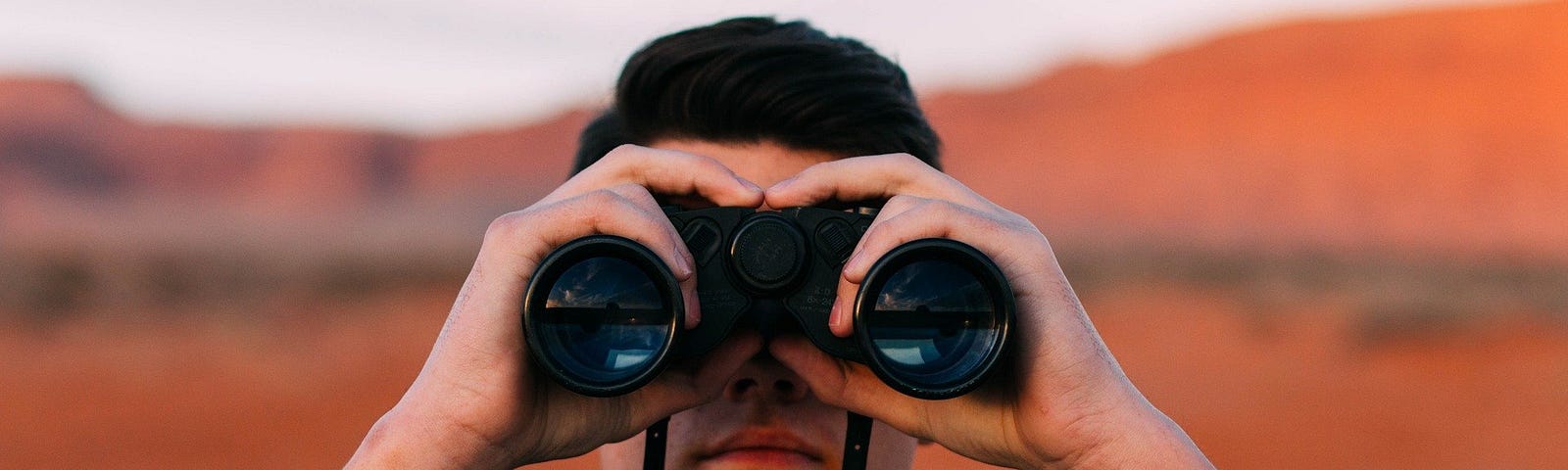 A man using a binoculars looking ahead