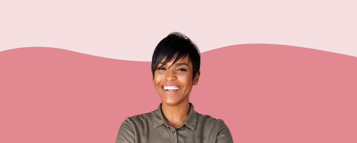 Confident, happy woman smiling against a pink background