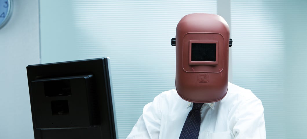 Man in a metal helmet staring at computer monitor
