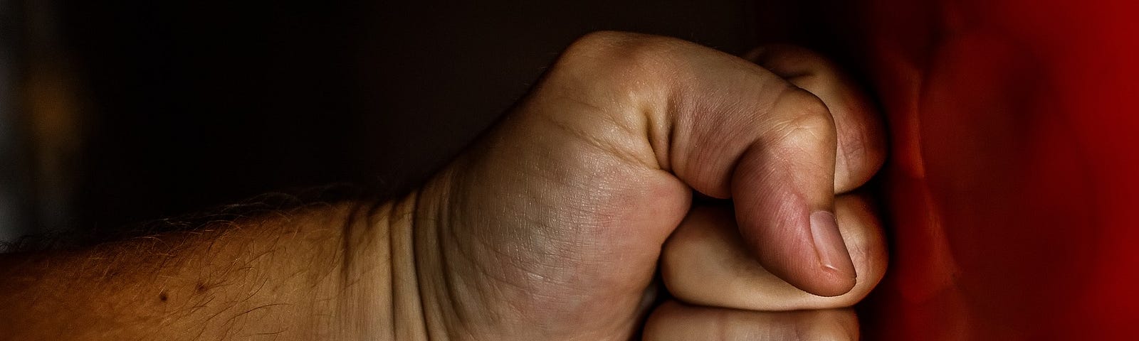 Close-up of a fist punching a punching-bag.