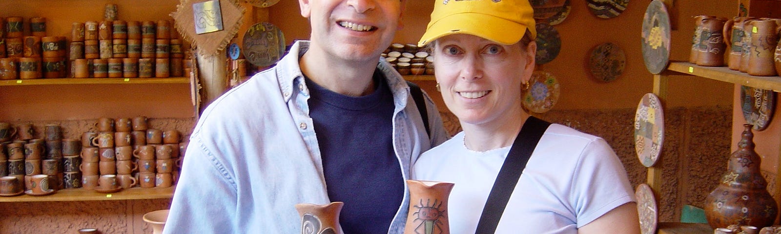 Man and woman holding handmade ceramic pitchers in shop