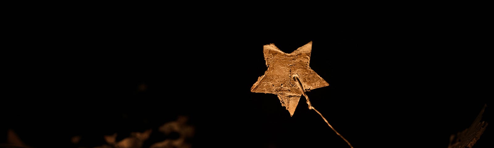 Small gold star suspended above candle flame with black background