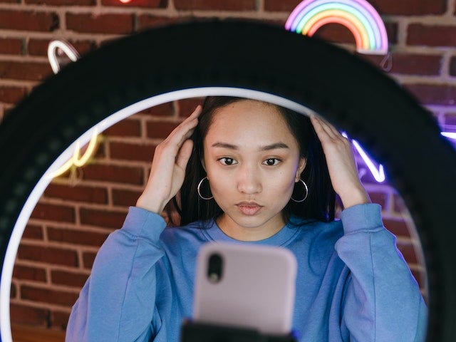 An influencer standing in frontof a ring light and phone