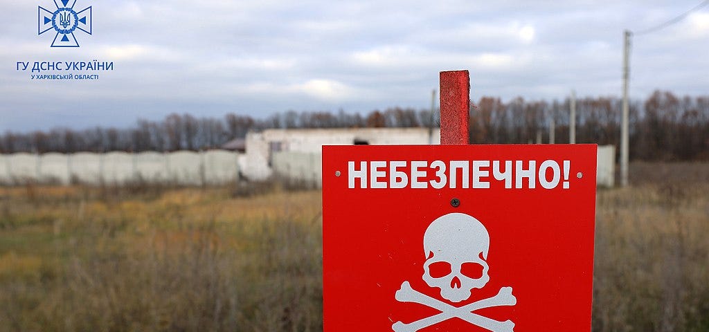 IMAGE: A red sign in Ukrainian reading “MINES” in a minefield in Kharkiv Oblast