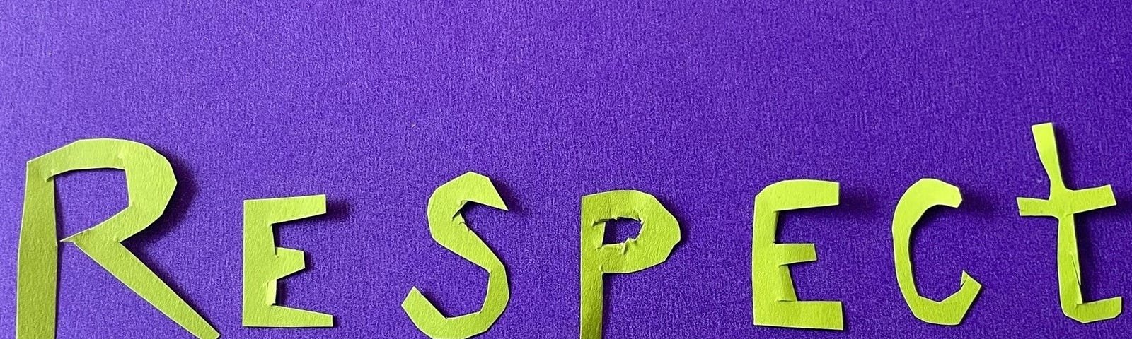 The word “Respect” cut from green paper and laid on a purple background.