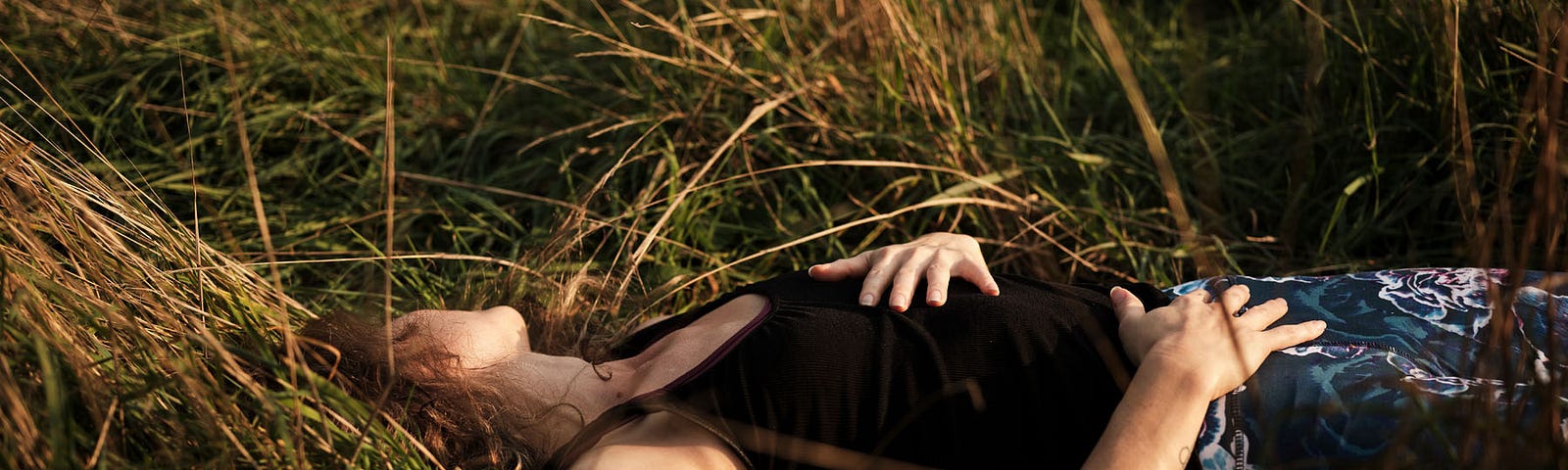 Woman lying on the ground with hands resting protectively on her heart and pelvis