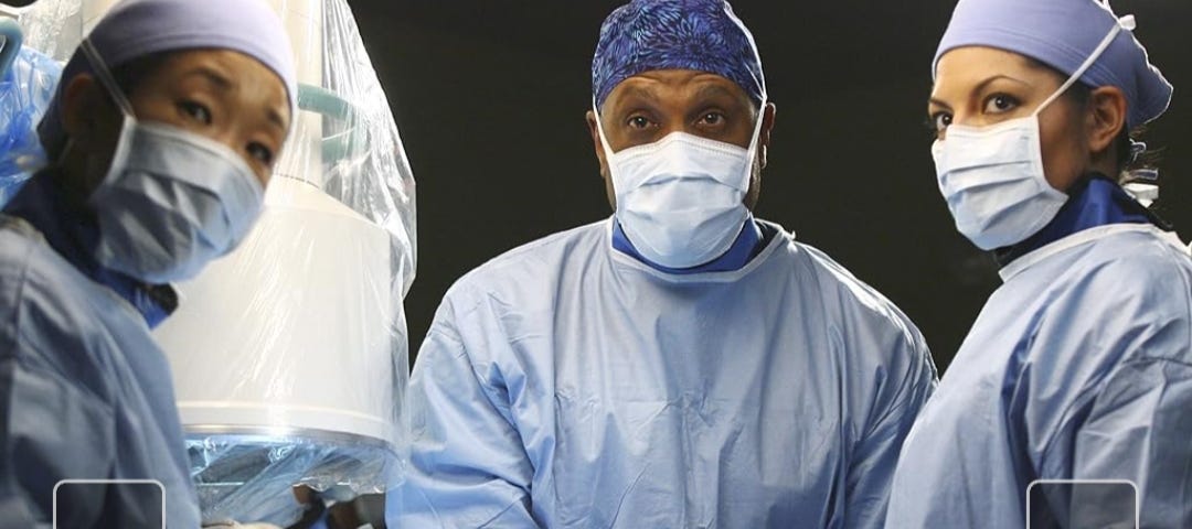 3 surgeon doctors — 1 man and 2 women, at the surgery table, wearing masks and feeling smart