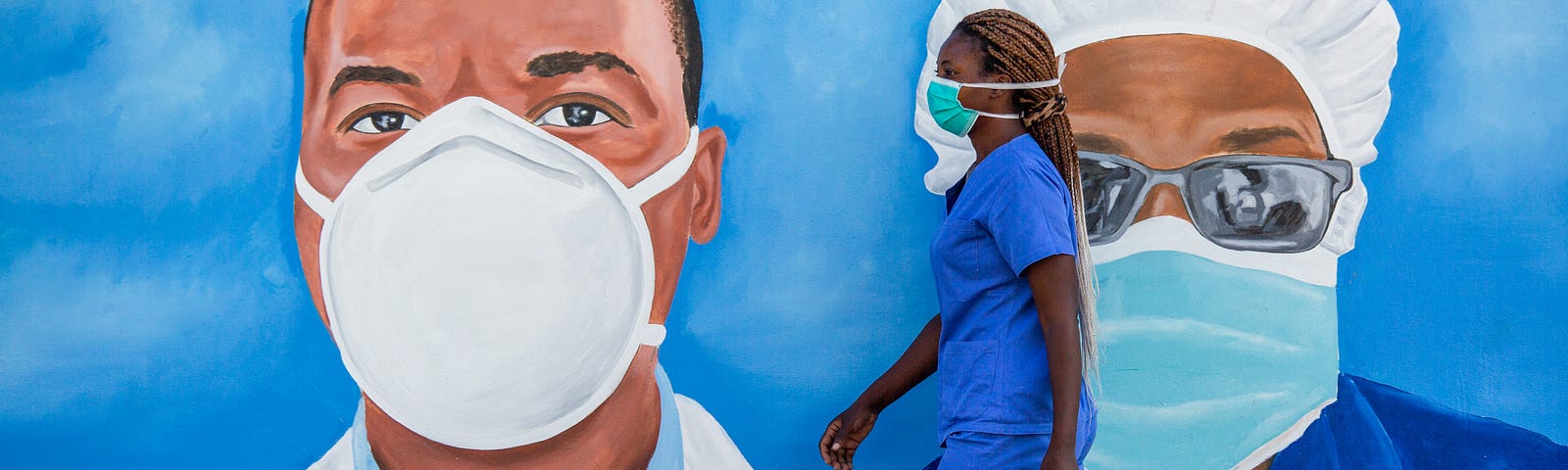 A health care worker walks past a mural at the Polana Caniço hospital in Maputo, Mozambique.