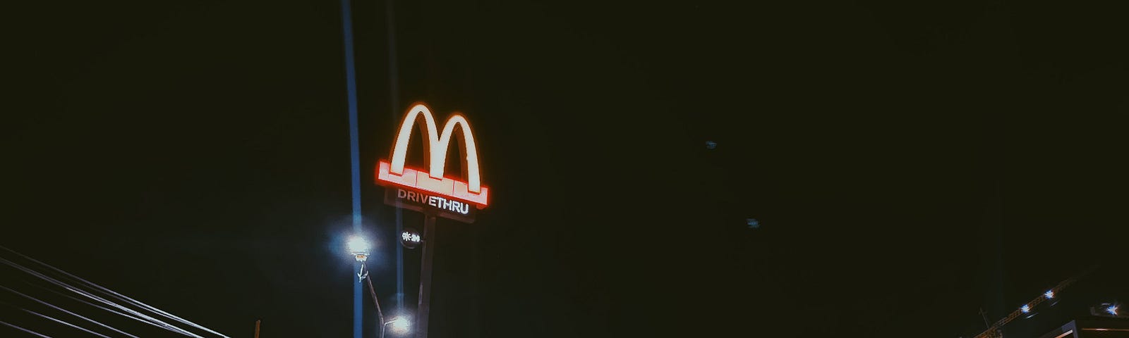 A McDonalds sign illuminated at night.