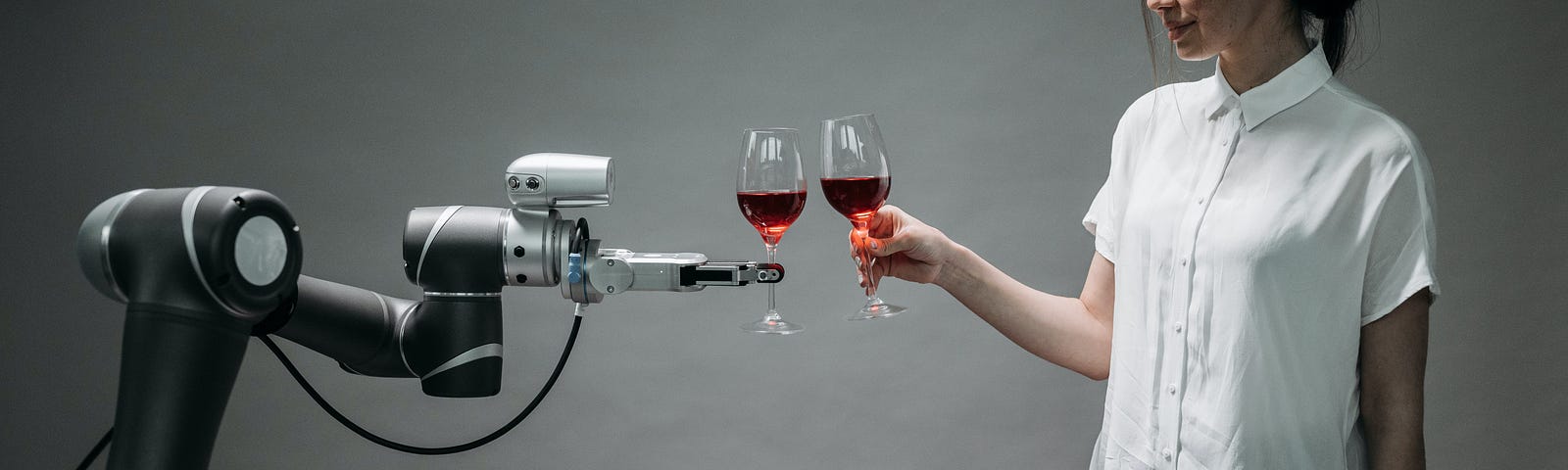 a robot holding a glass of wine and clinking it against the glass of wine a woman is holding. She is smiling slightly.