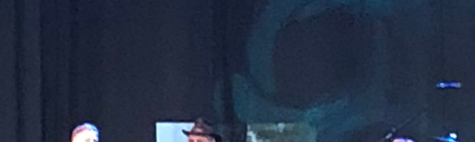 Three performers on stage — left to right, a male bass player (John Billings), a male singer (Micky Dolenz) and a female singer (Coco Dolenz)