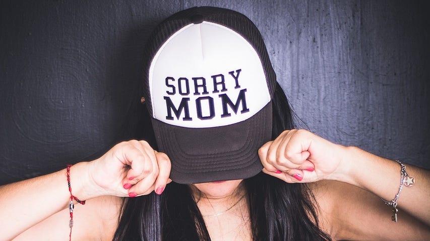 A woman wearing a cap with the message “Sorry mom.”