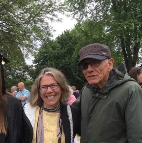 The author smiles standing next to an older gentleman with one darkened lens.