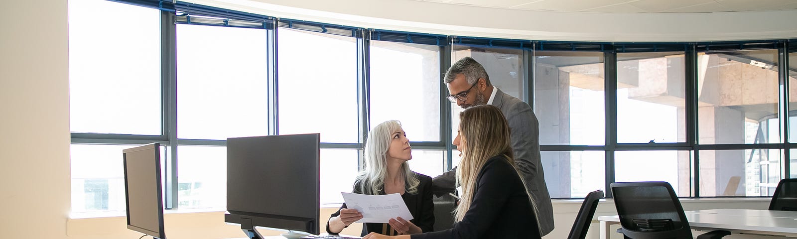 Managers sitting at a table in an office discussing a report.