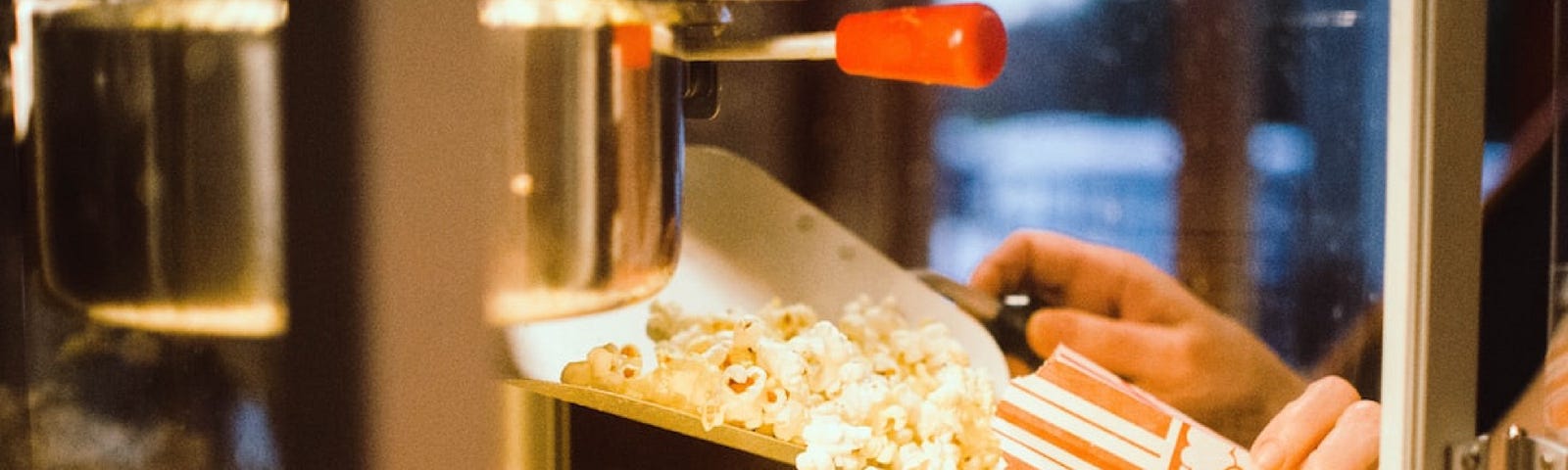 Server scoops popcorn out of machine at a movie theatre