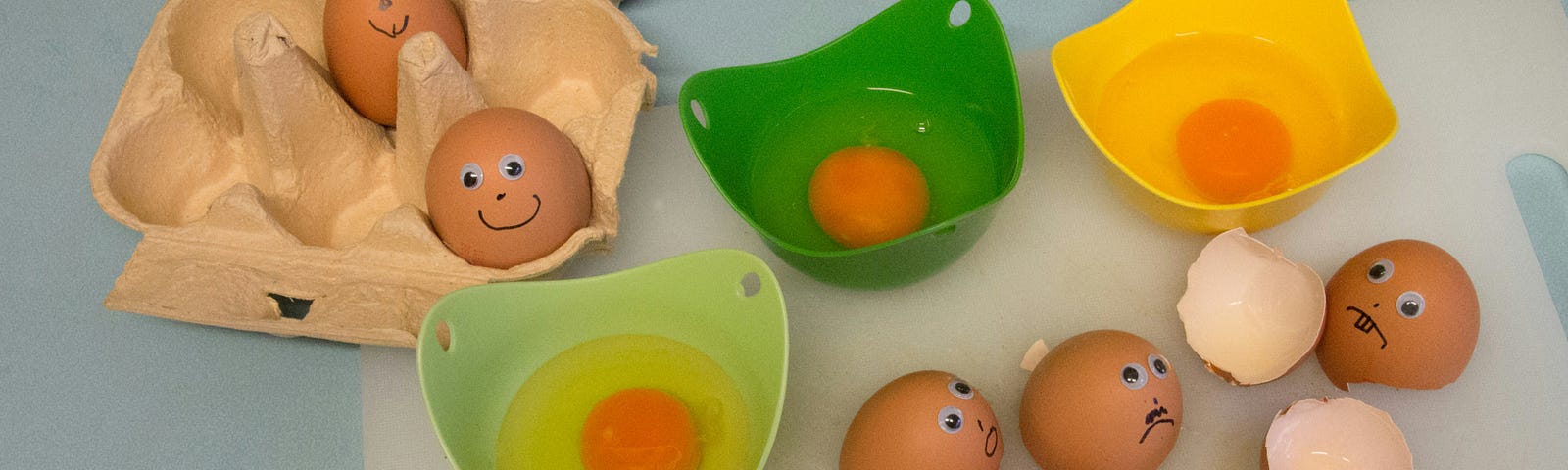 There are 3 colored bowls with eggs. Yellow, dark green, and lime green. Some of the eyes have drawn on happy faces while some look sad.